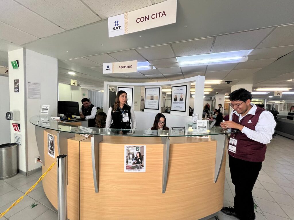 Módulo de atención del SAT con personal atendiendo a contribuyentes en área de registro y citas.