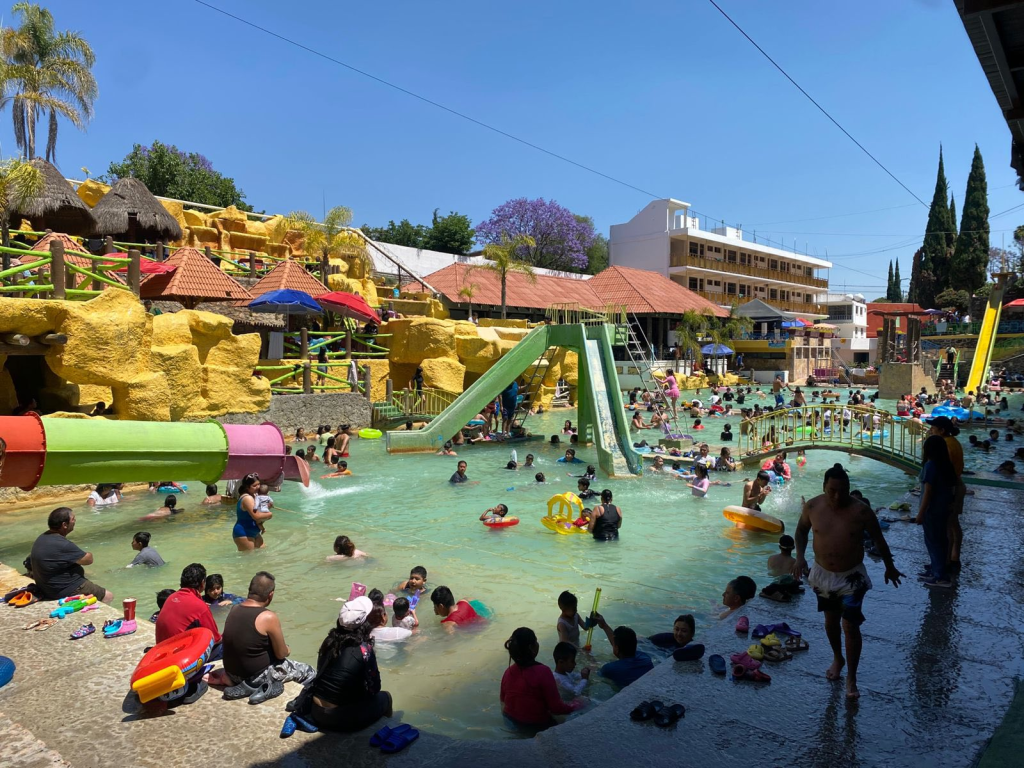 Alta afluencia de visitantes en balneario de Hidalgo durante Semana Santa, con familias disfrutando albercas y toboganes en un día soleado