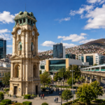 Vista del Reloj Monumental de Pachuca rodeado de edificios modernos, infraestructura urbana y un tren de pasajeros, imagen que representa el crecimiento económico, la competitividad y el desarrollo de la capital hidalguense.