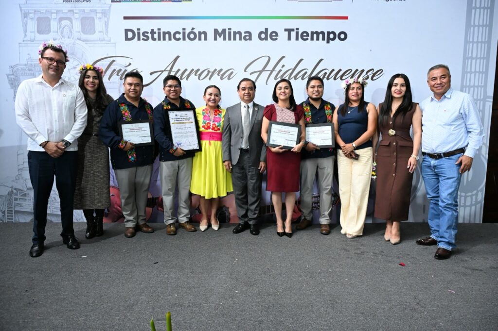 Integrantes del Trío Aurora Hidalguense y autoridades se toman una fotografía durante la ceremonia de reconocimiento.