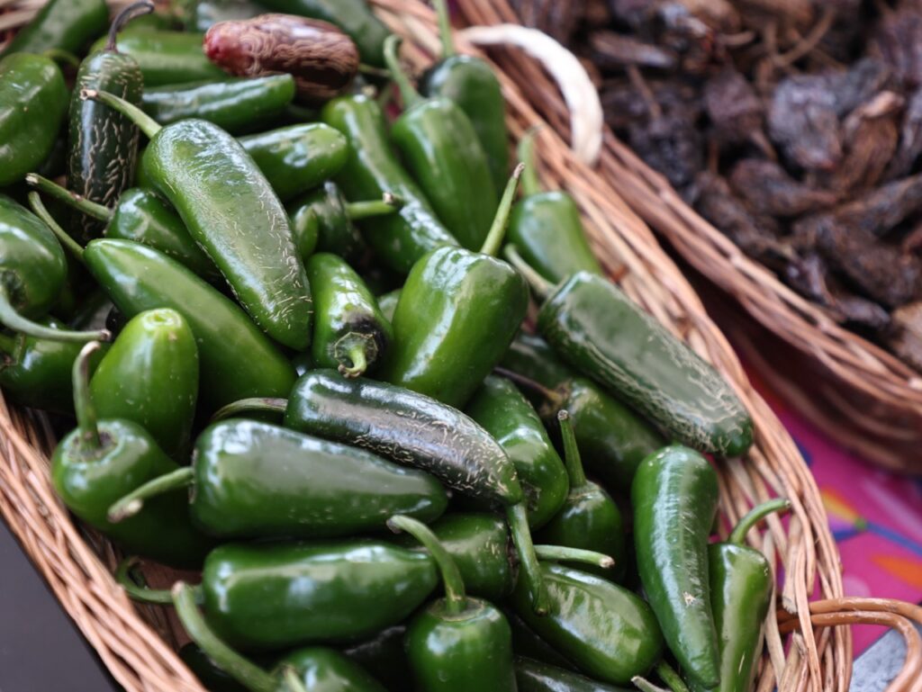Canasta con chiles rayados frescos de color verde, utilizados para la elaboración de uno de los productos gastronómicos más representativos de la Sierra Gorda de Hidalgo, exhibidos durante una muestra de productores locales.