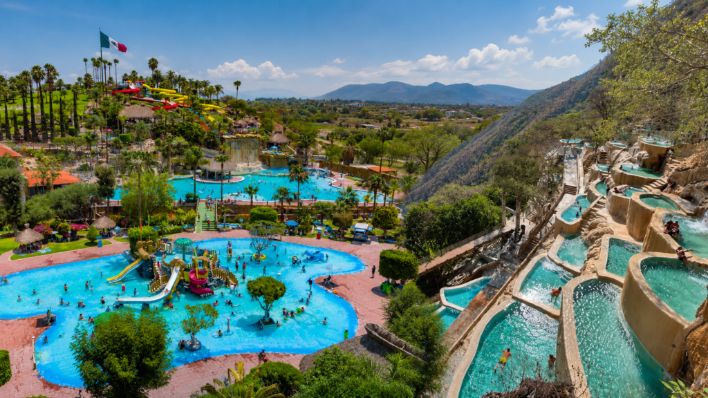 Vista panorámica de balnearios en Hidalgo con piscinas de aguas termales, áreas recreativas y visitantes rodeados de paisajes montañosos.