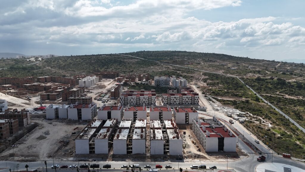 Vista aérea de un desarrollo habitacional en Hidalgo, con edificios de vivienda en construcción, vialidades e infraestructura urbana