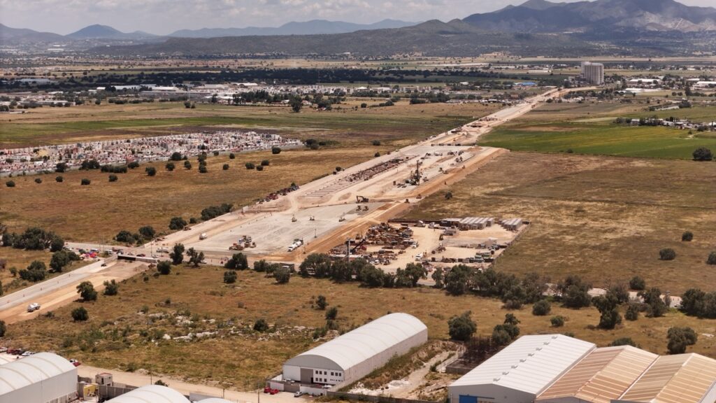 Vista aérea de las obras de construcción del Tren México-Pachuca, rodeadas de campos, viviendas y zonas industriales en Hidalgo.